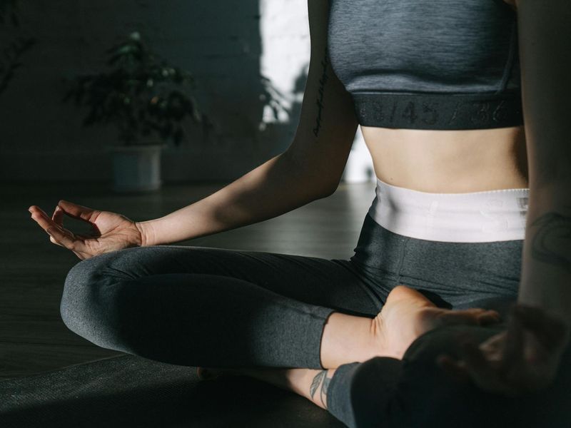 Woman in a flowing yoga pose on a mat in a bright, minimalist room.